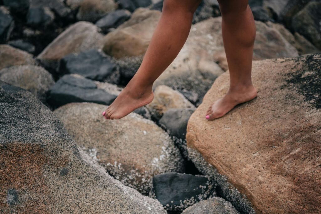 Close-up view of bare feet balancing on rocky terrain outdoors.